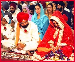 Sikh couple sitting in the presence of the Sri Guru Granth Sahib